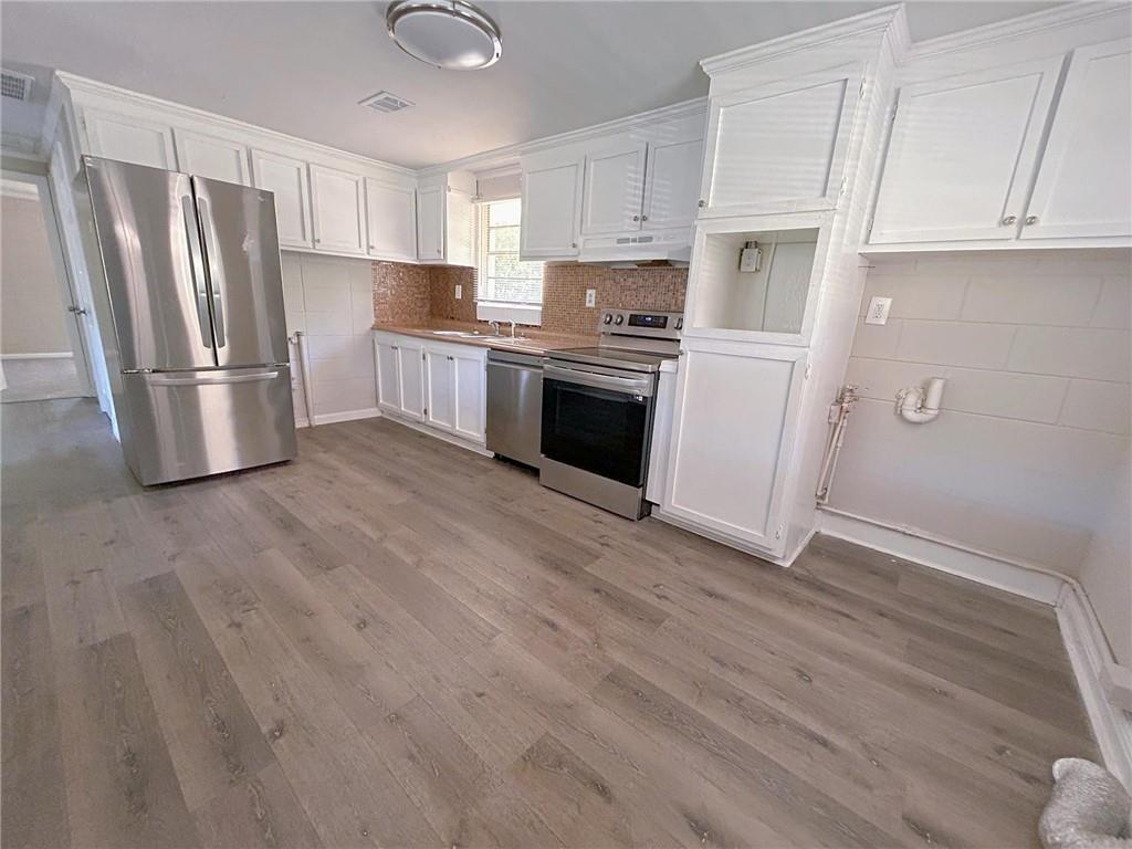 271 Rehoboth Road Griffin, GA 30223 - Photo 6 of 9 a kitchen with granite countertop a refrigerator oven a sink dishwasher and white cabinets with wooden floor