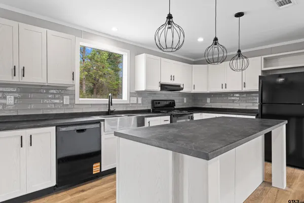 a kitchen with a sink a counter space appliances and cabinets