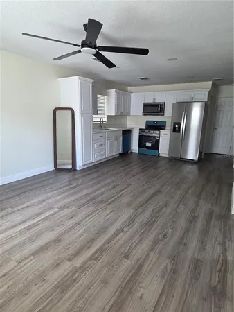 a view of an empty room with kitchen and a window