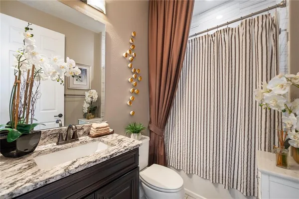 a bathroom with a granite countertop sink and a toilet
