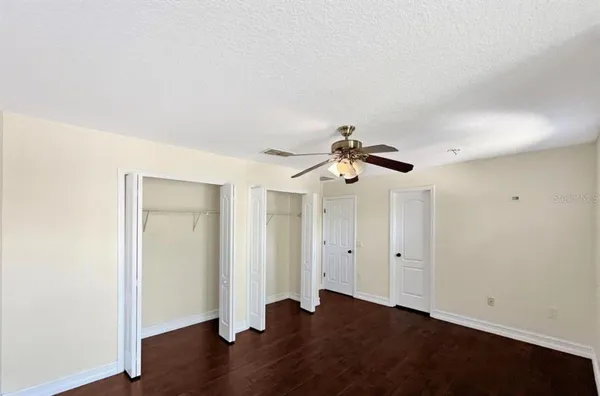 an empty room with wooden floor and ceiling fan