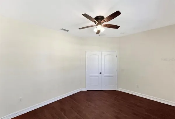 an empty room with wooden floor fan and windows