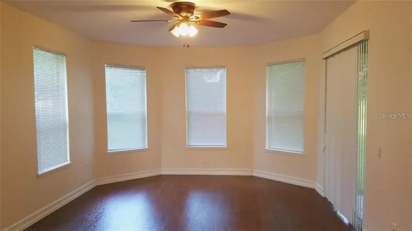 a view of an empty room with wooden floor and a window