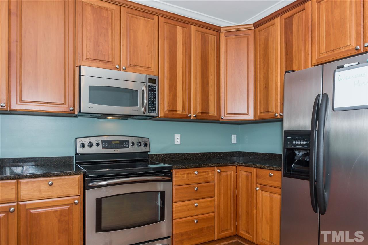 610 Highpark Lane Raleigh, NC 27608 - Photo 13 of 25 a kitchen with granite countertop a stove microwave and refrigerator with wooden floor