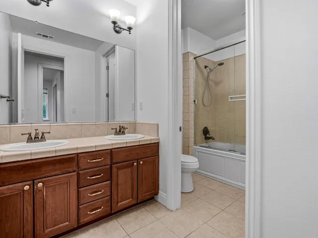 a bathroom with a tub a sink double vanity and a mirror