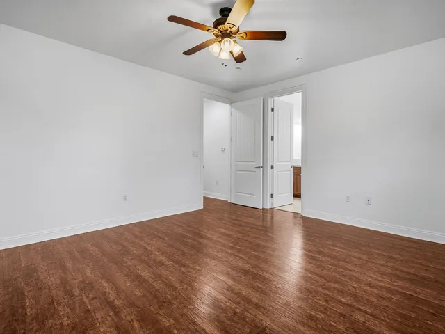 a view of an empty room and window a ceiling fan and wooden floor