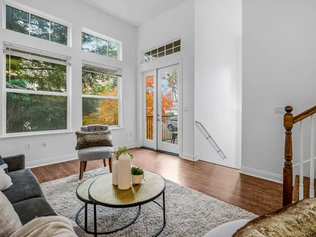 a living room with furniture a large window and wooden floor