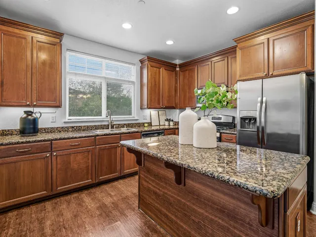 a kitchen with kitchen island granite countertop a stove a sink cabinetry and a refrigerator