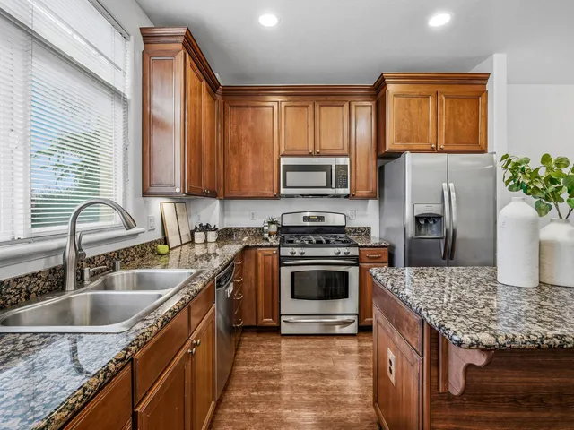 a kitchen with kitchen island granite countertop a sink stove and refrigerator