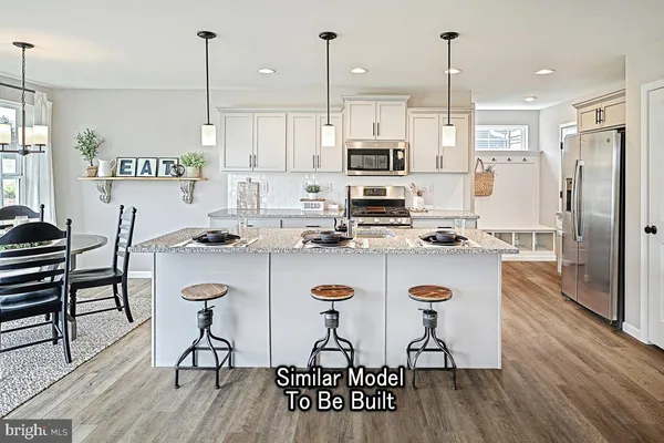 a kitchen with stainless steel appliances kitchen island a refrigerator a stove a sink and chairs