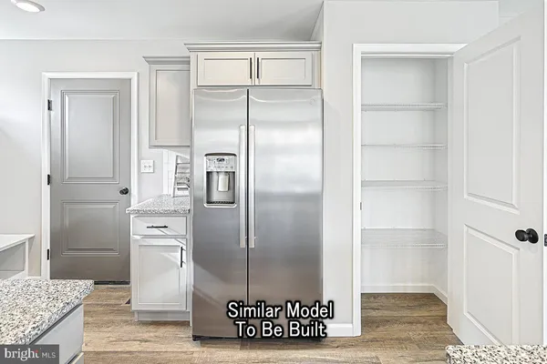 a view of a kitchen with refrigerator and wooden floor