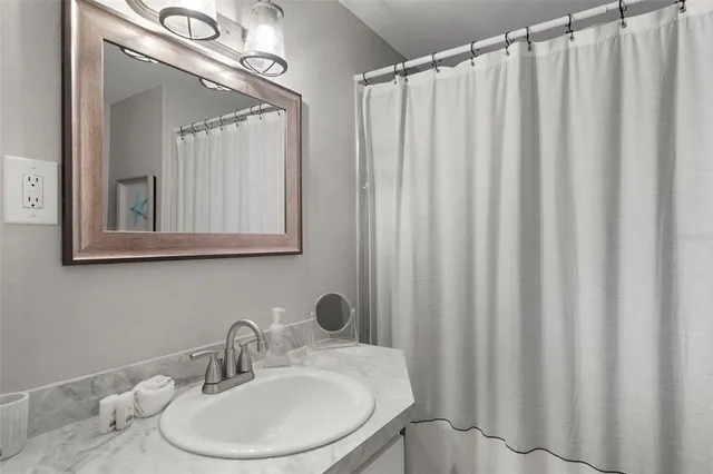 a bathroom with a sink a mirror and a shower curtain