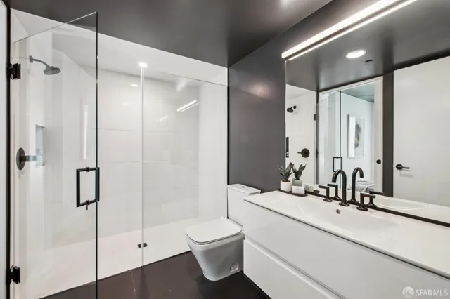 a bathroom with a double vanity sink toilet mirror and shower