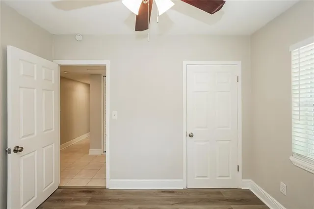 an empty room with wooden floor cabinet and windows