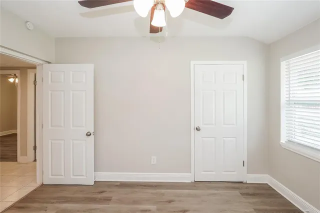 an empty room with wooden floor closet and windows