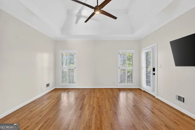 a view of an empty room with wooden floor and a window