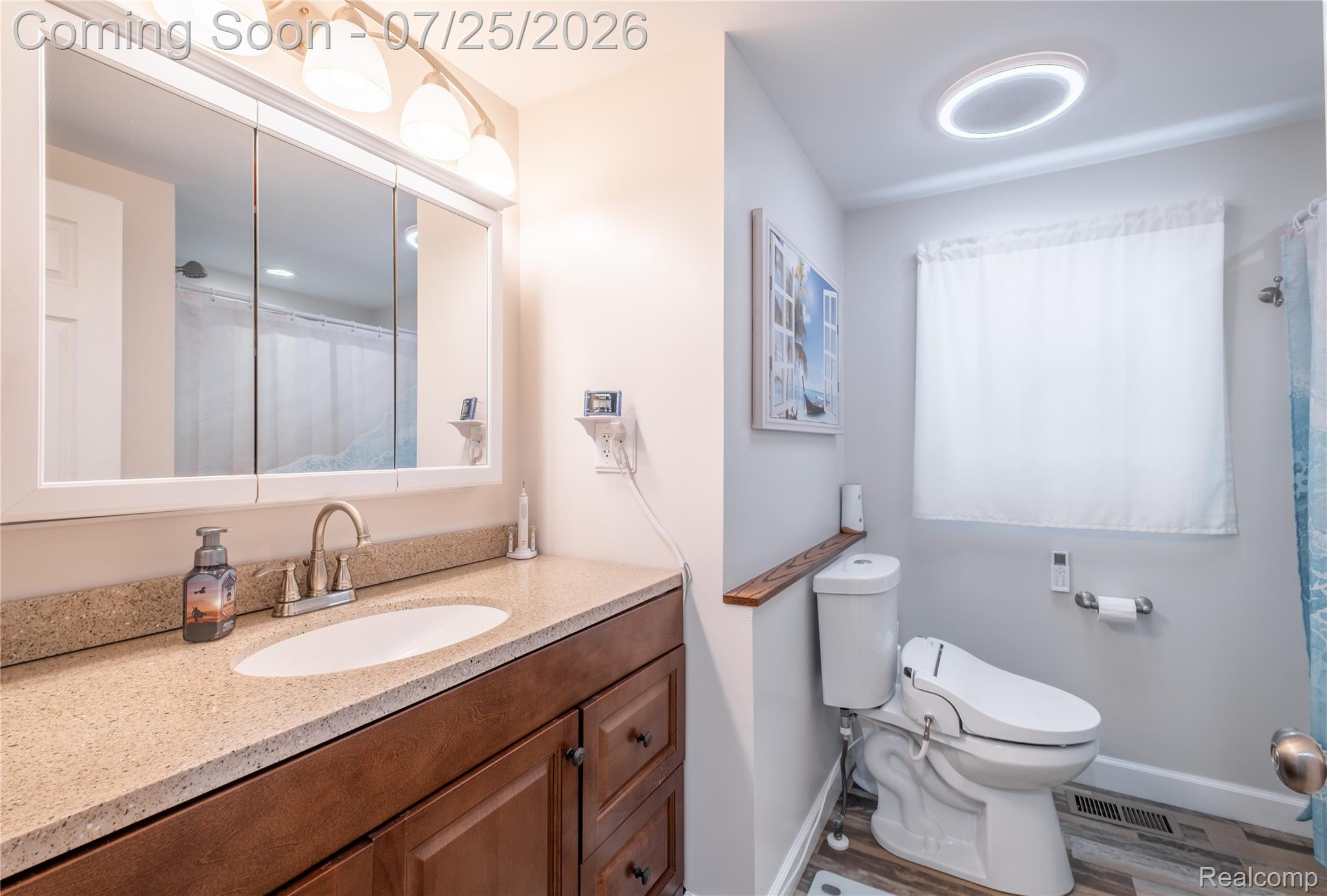 4057 Risedorph Street Burton, MI 48509 - Photo 19 of 23 Bathroom vanity featuring a light-toned countertop, an undermount sink, and a wood-finish cabinet with multiple drawers and doors