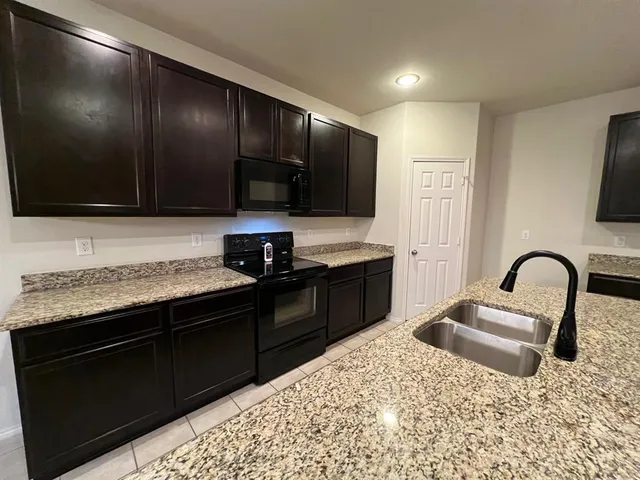 a large kitchen with granite countertop a sink and a stove