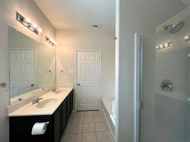 a spacious bathroom with a double vanity sink a toilet and a mirror