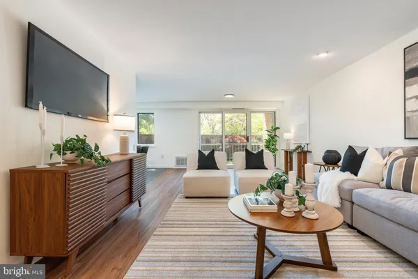 a living room with furniture kitchen view and a flat screen tv