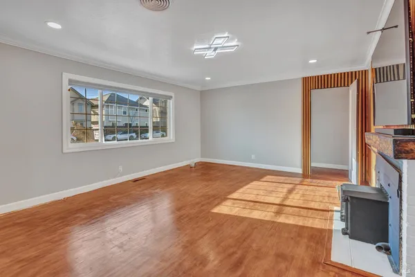 a view of an empty room with window and wooden floor