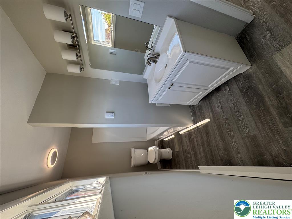 702 Walnut Street, Unit 2 Freeland, PA 18224 - Photo 7 of 8 A well-lit bathroom features a vanity with dual sinks, a large mirror, and durable wood-look flooring.