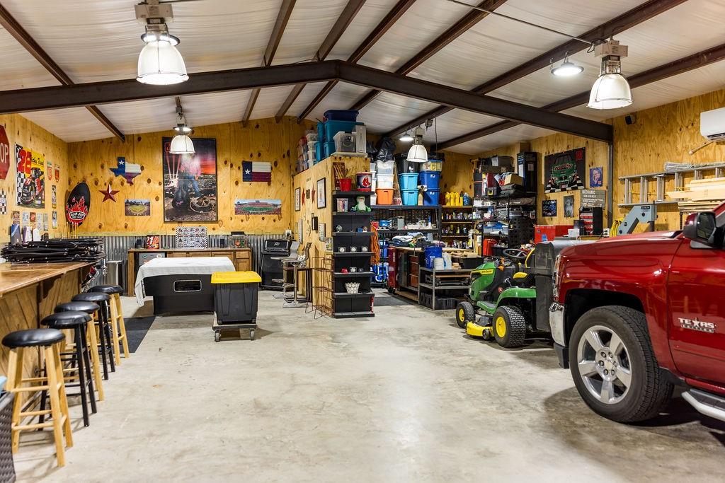 123 Cactus Drive Decatur, TX 76234 - Photo 25 of 30 Spacious interior with exposed structural beams, plywood wall finishes, concrete flooring, and multiple ceiling-mounted light fixtures