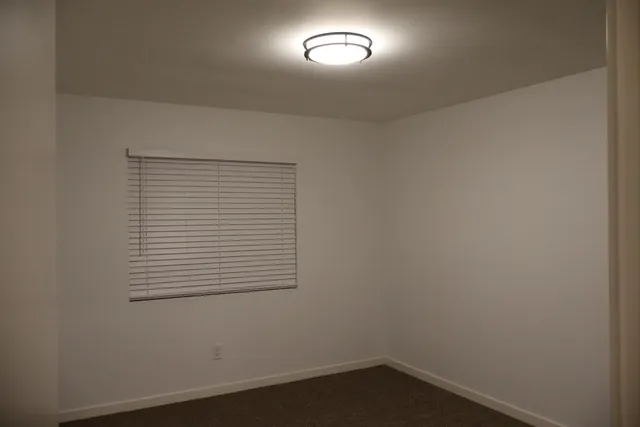a view of an empty room with wooden floor and a ceiling fan
