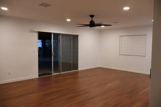 an empty room with wooden floor and natural light