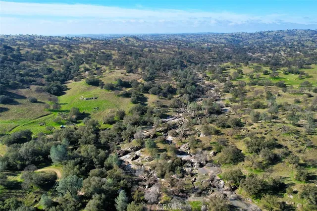 an aerial view of residential house with parking and trees
