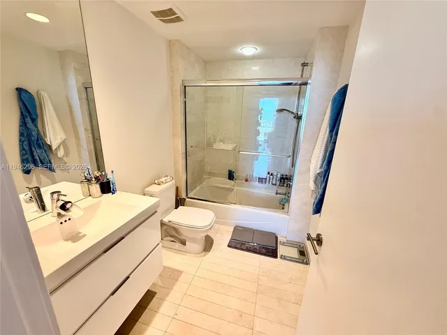 a bathroom with a sink a toilet and a large mirror