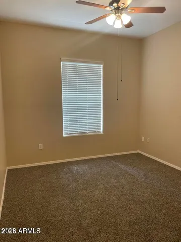 an empty room with a chandelier fan and windows