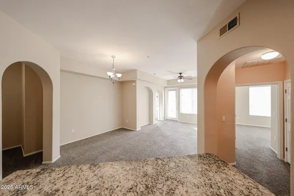 an empty room with a chandelier fan and windows