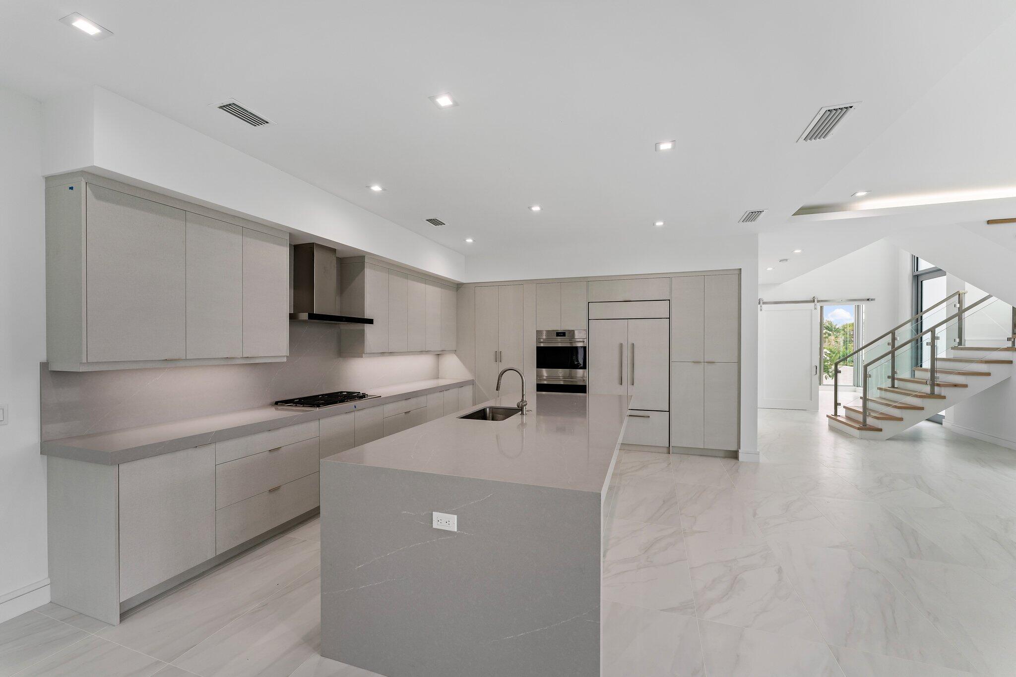 423 Ocean One Lane Juno Beach, FL 33408 - Photo 17 of 58 a kitchen with stainless steel appliances a sink a stove a refrigerator cabinets and a dining table