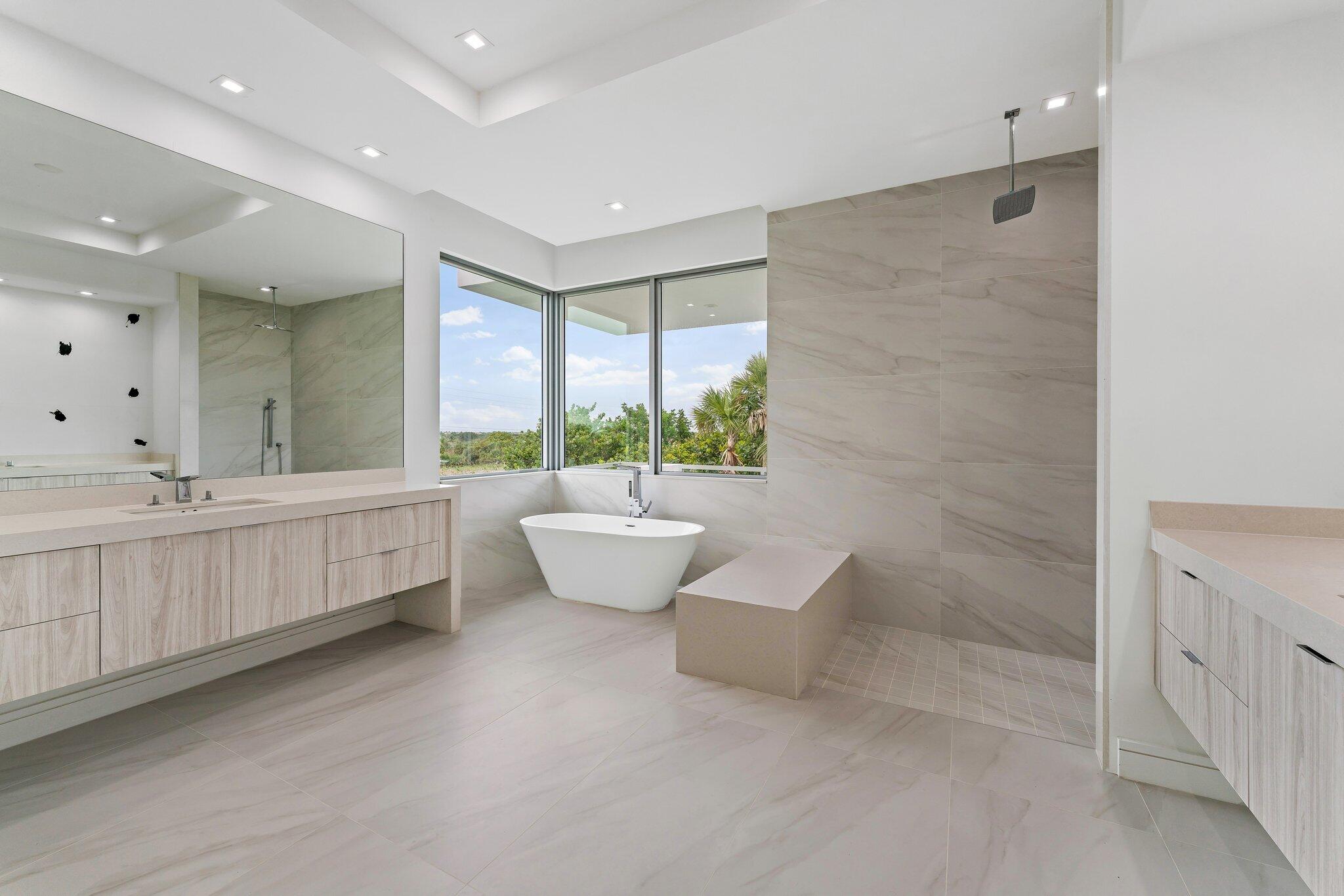 423 Ocean One Lane Juno Beach, FL 33408 - Photo 35 of 58 a spacious bathroom with a double vanity sink a large mirror and a bathtub