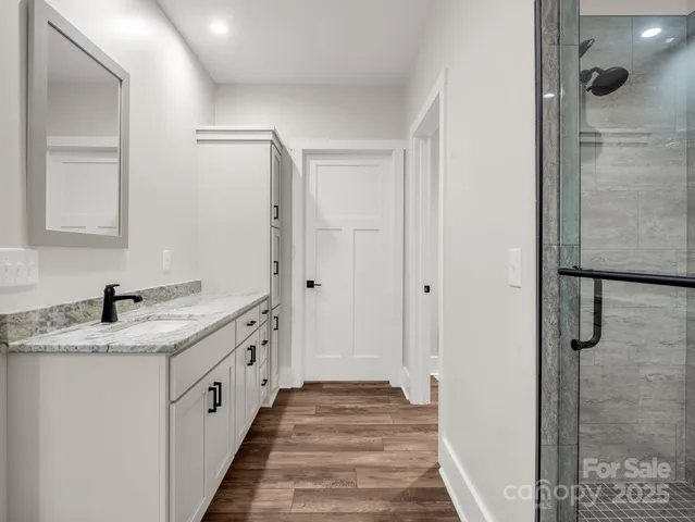 a spacious bathroom with a granite countertop sink a mirror and shower