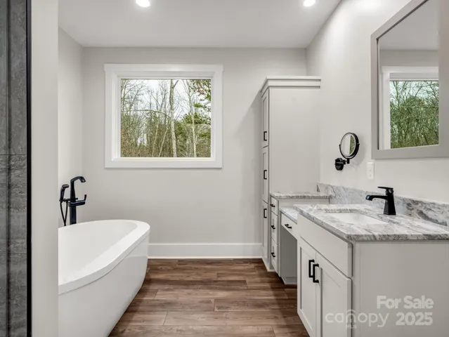 a bathroom with a granite countertop sink mirror and a bathtub
