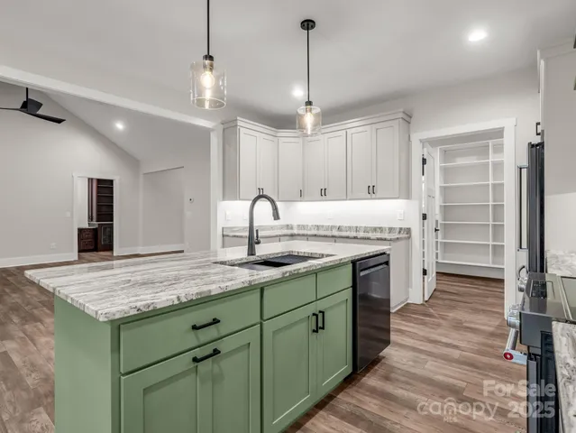 a kitchen with kitchen island granite countertop a oven a counter space and wooden floor
