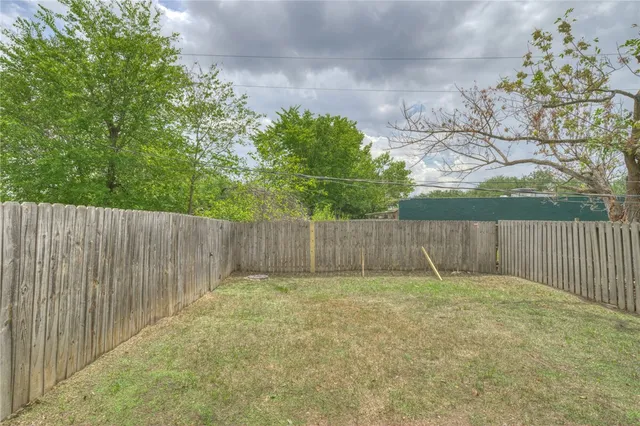 a view of a backyard with a large tree and wooden fence