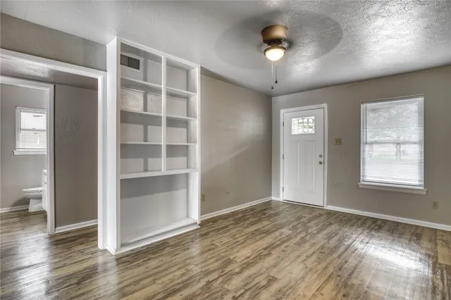 a view of an empty room with a window and wooden floor