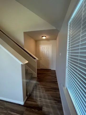 a view of a hallway with wooden floor and staircase