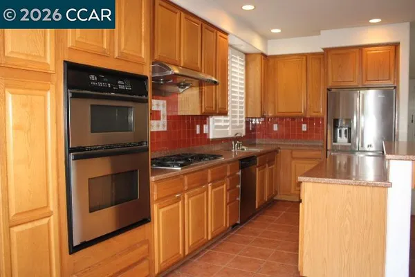 a kitchen with stainless steel appliances granite countertop a stove a sink and a refrigerator