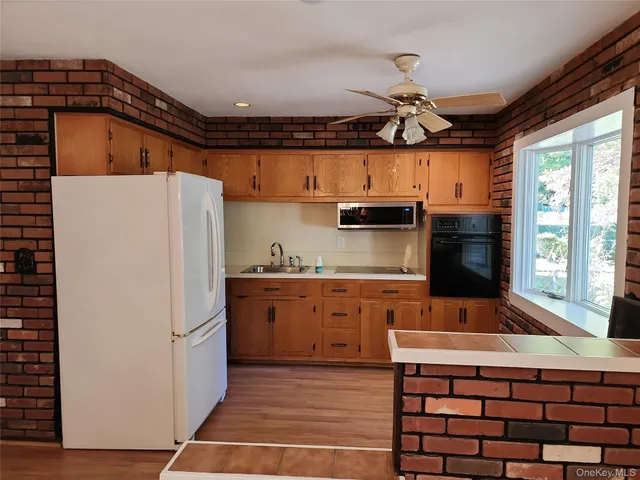 a kitchen with stainless steel appliances granite countertop a refrigerator a sink dishwasher a stove and a dining table with wooden floor