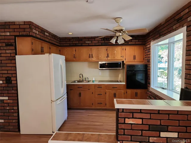 a kitchen with stainless steel appliances granite countertop a refrigerator a sink dishwasher a stove and a dining table with wooden floor