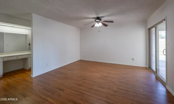 a view of empty room with wooden floor and fan