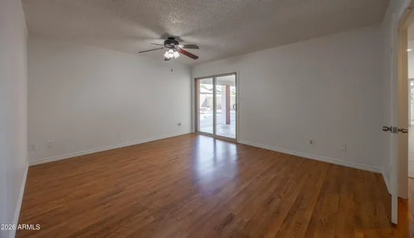 a view of an empty room with wooden floor and a chandelier fan