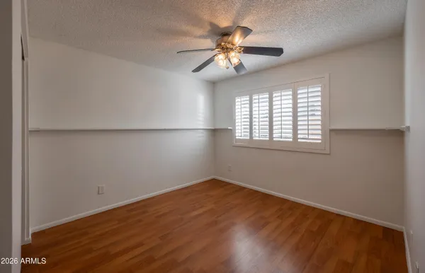an empty room with wooden floor fan and windows