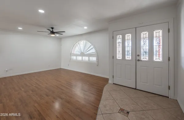 a view of empty room with wooden floor and fan