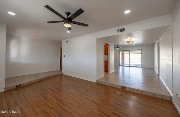 an empty room with wooden floor and a ceiling fan