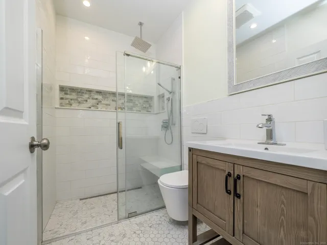 a bathroom with a sink a toilet a mirror and shower